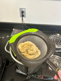 Yellow dyed wool sits in a strainer, draining out the excess liquid.