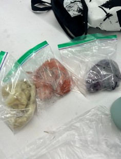 Three plastic baggies with small amounts of yellow, orange, and purple dyed wool.