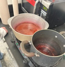 Two pots on burners with dye extracts cooking (cochineal and logwood).