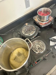 Two pots of roving cooking in dye on the stove (yellow osage and red cochineal).