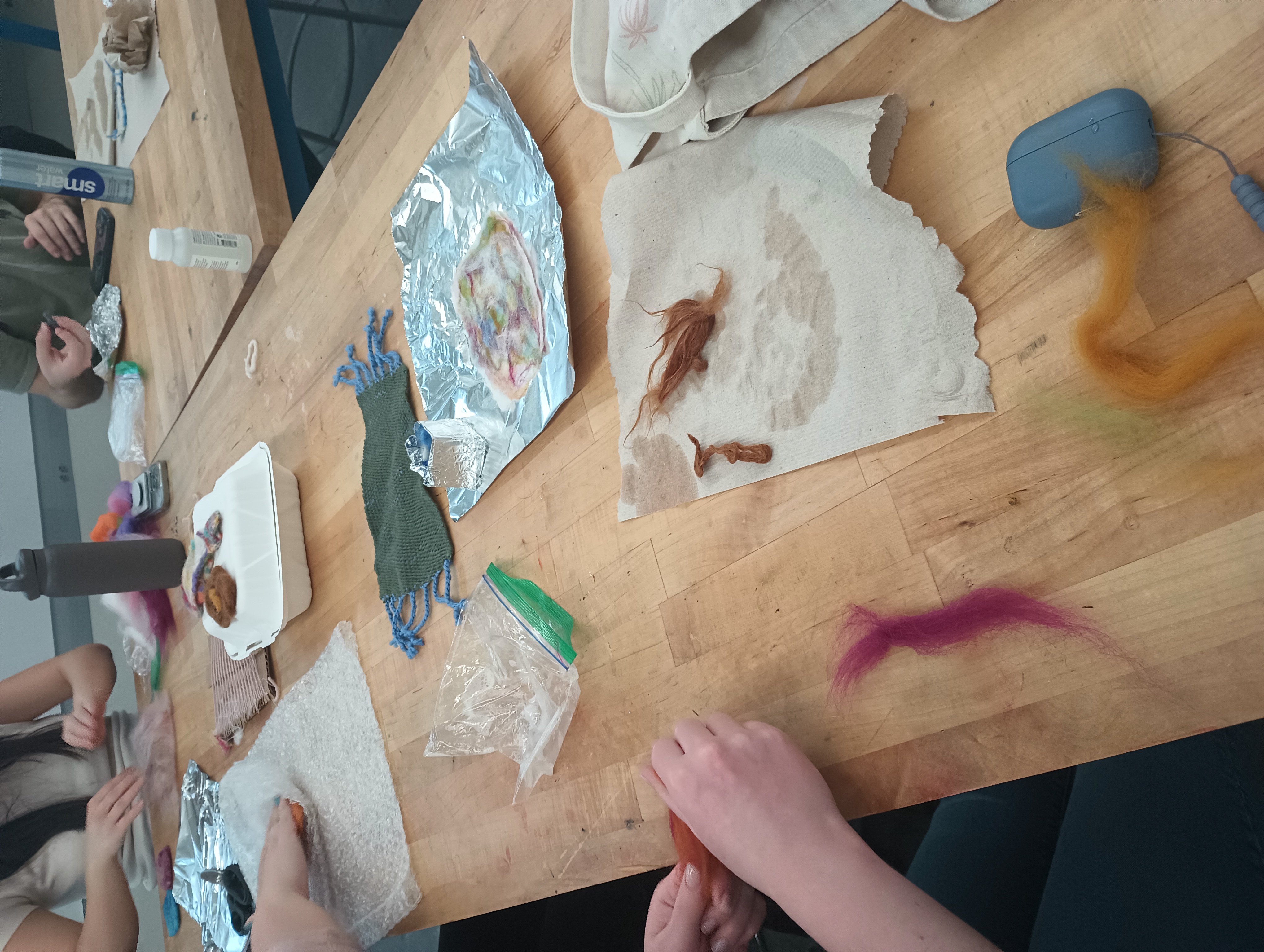 A student tears off small pieces of colorful wool roving to prepare for felting.