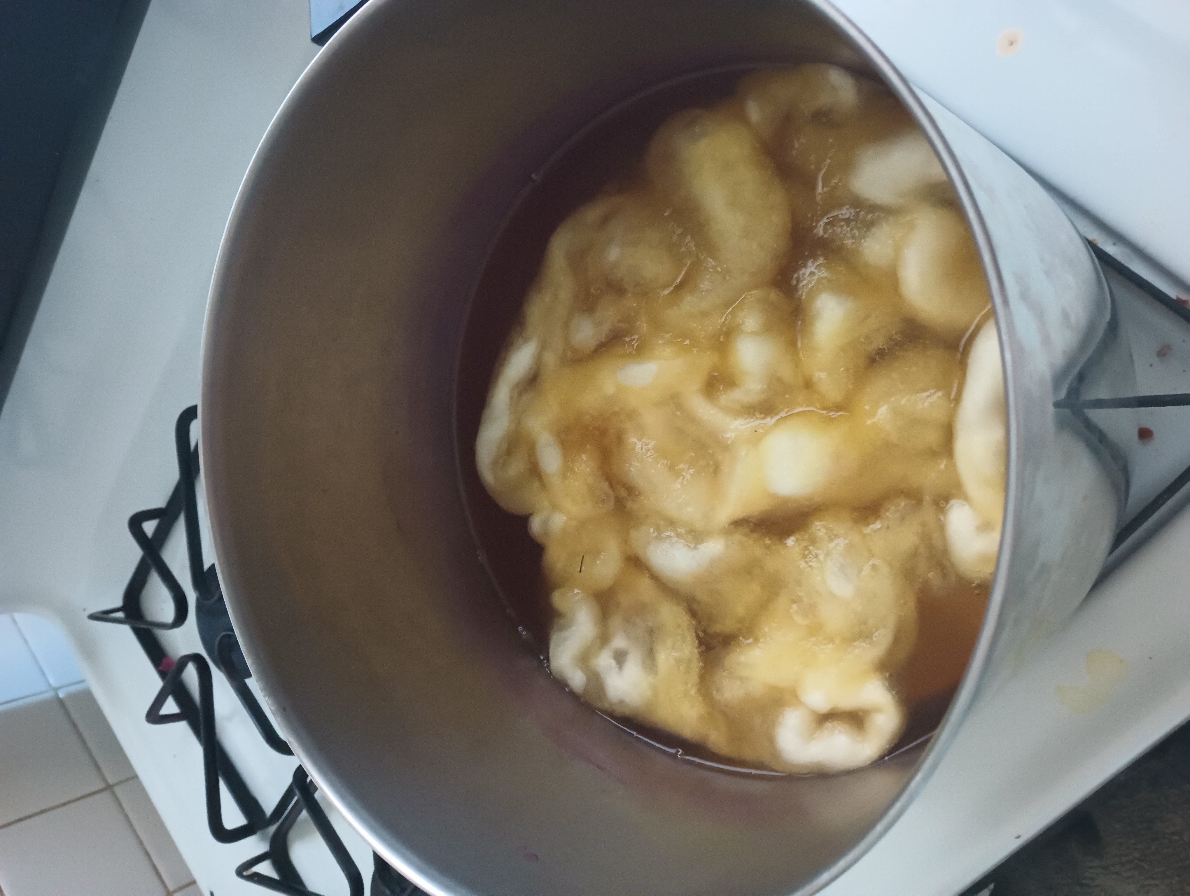 Wool roving cooks in a pot of pale yellow osage dye.