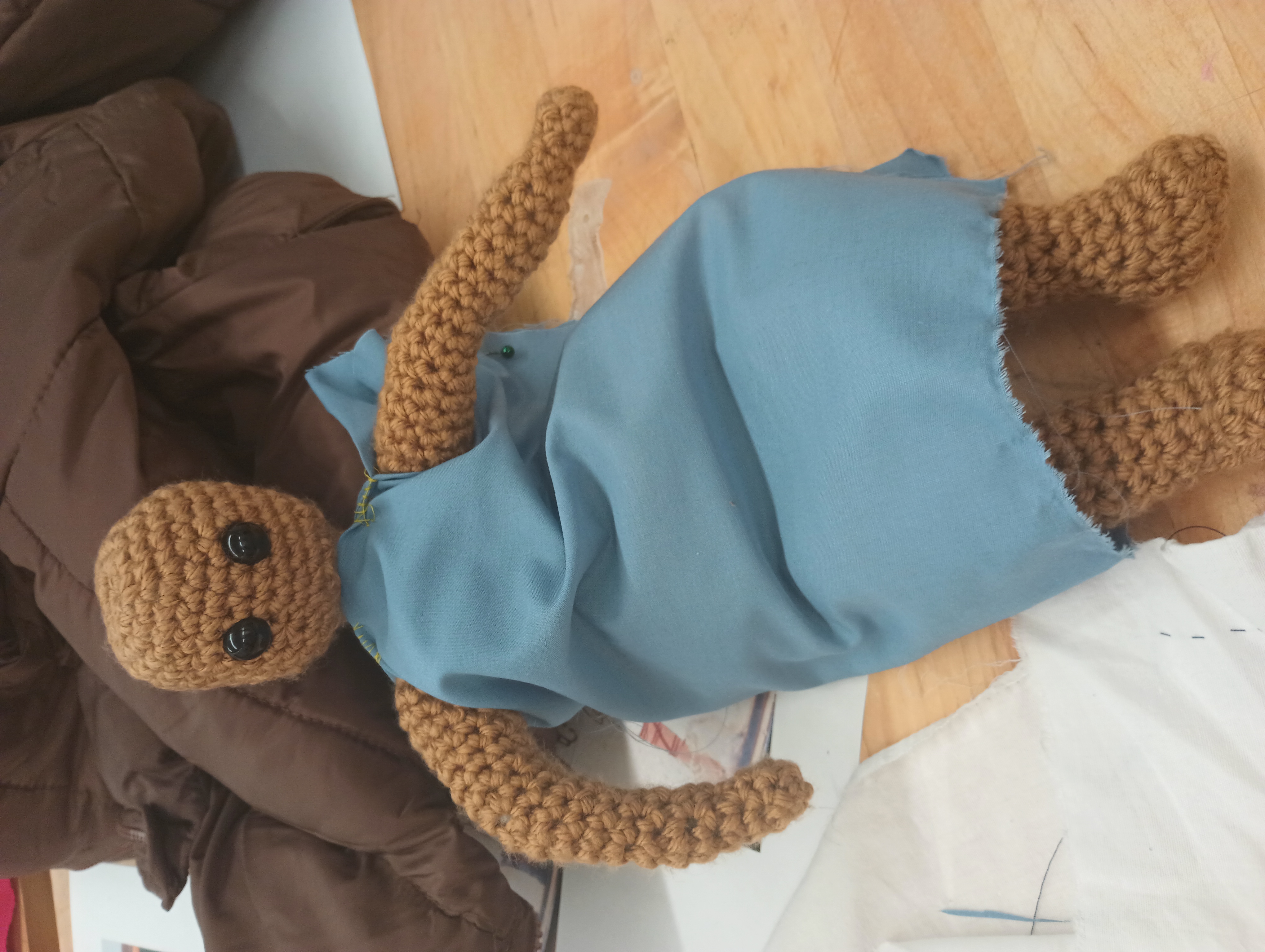 A crocheted art doll wears a blue unbelted dress.