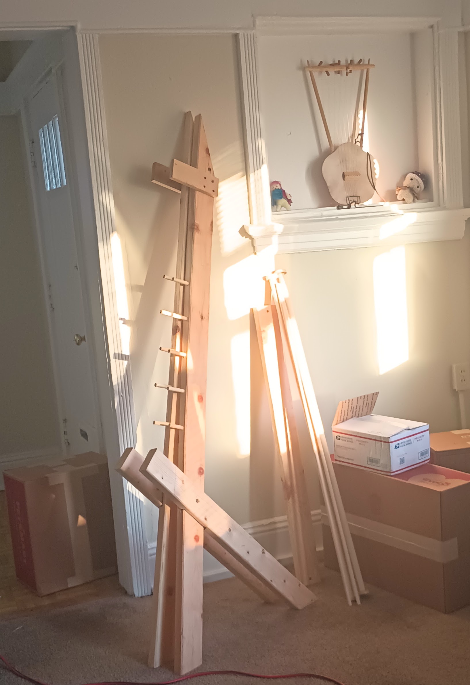 Disassembled pieces of a wooden warp-weighted loom lean against the wall of my living room.